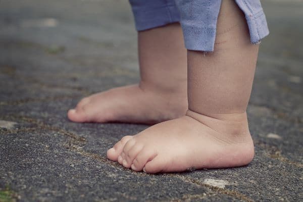 a small child walking on concrete without shoes