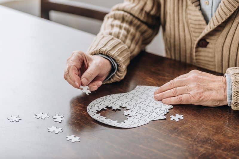 elderly man doing a jigsaw puzzle at a table