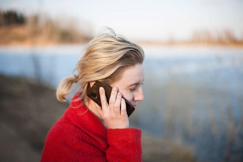 woman outside by a lake talking on a cell phone